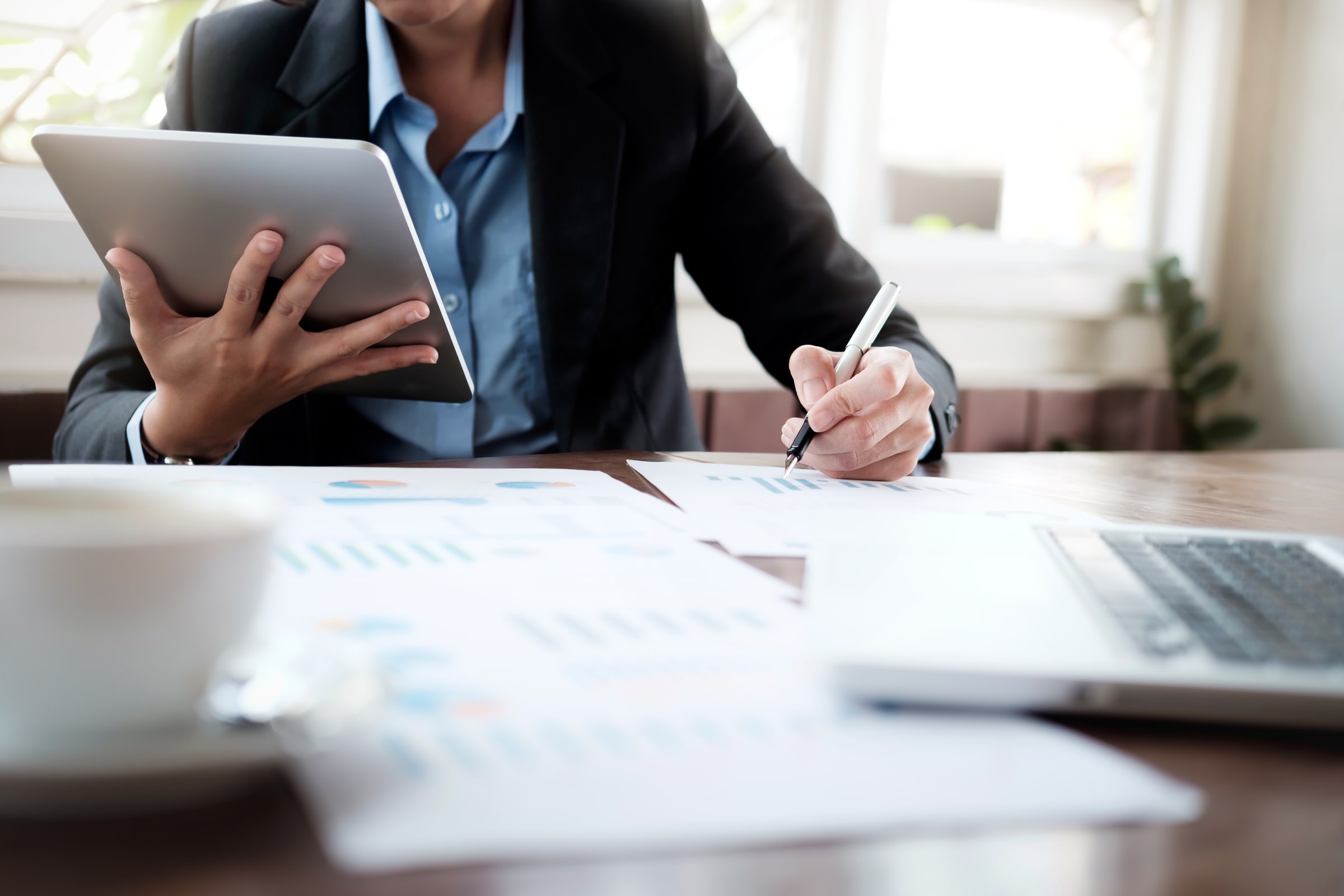 Dirigeante préparant son dossier de création d'entreprise avec une tablette et des documents